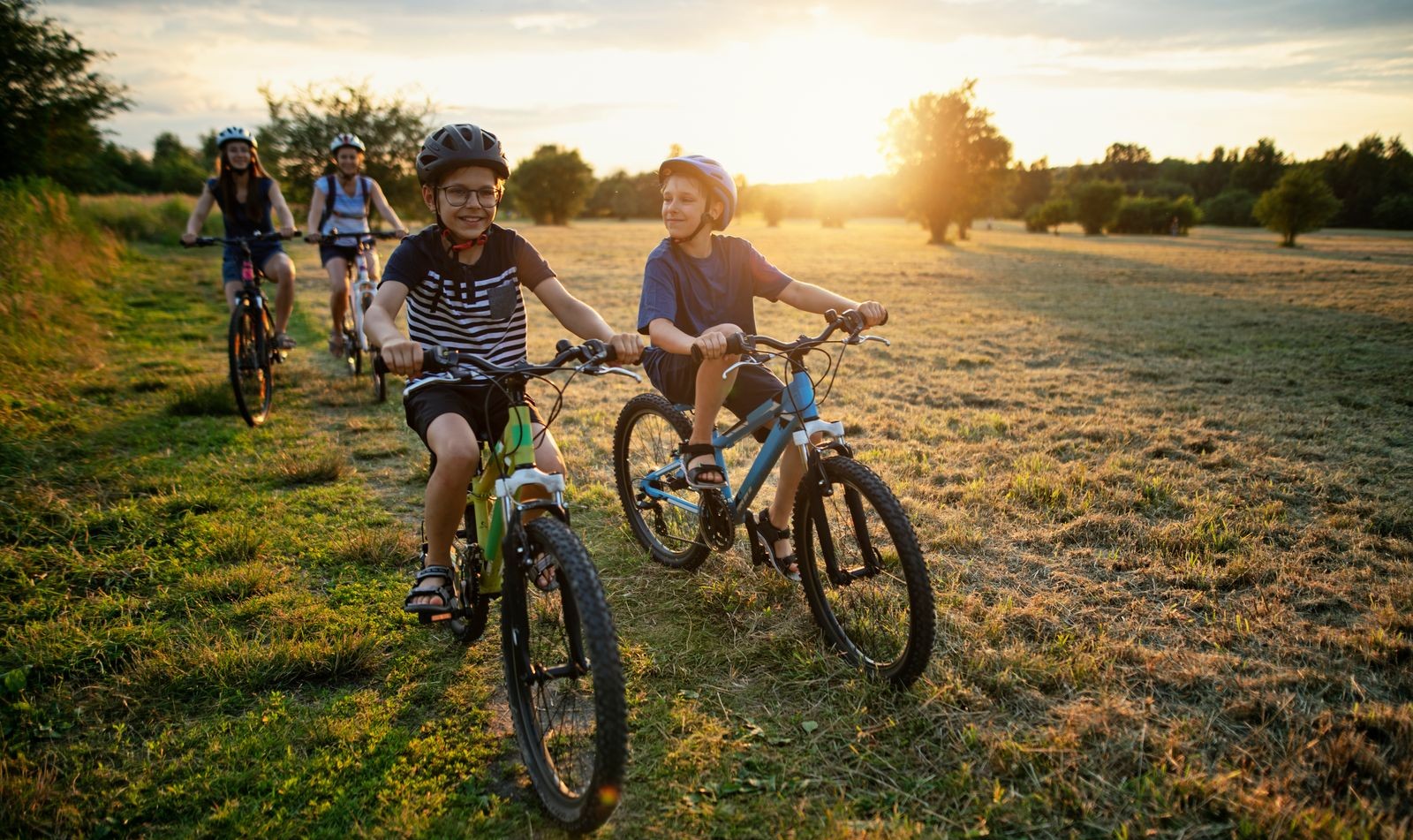 Una familia montando en bicicleta por un campo bañado por la luz del sol, con un cálido resplandor de fondo, lo que refleja el estilo de vida activo y al aire libre que se disfruta en Pasadena Ridge.